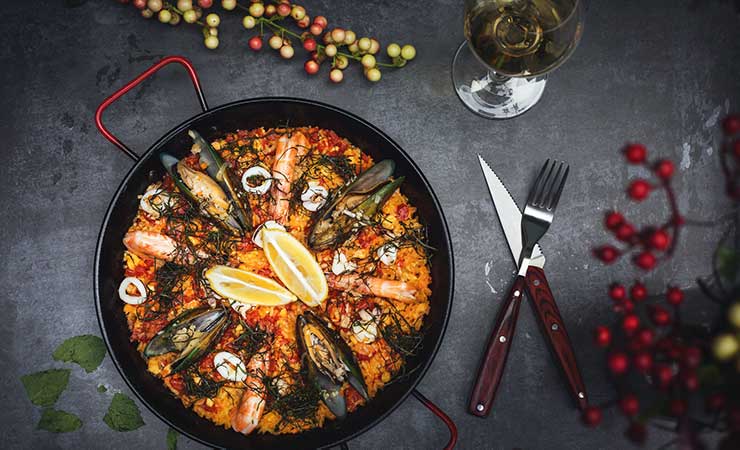 un piatto di paella ai frutti di mare con calice di vino